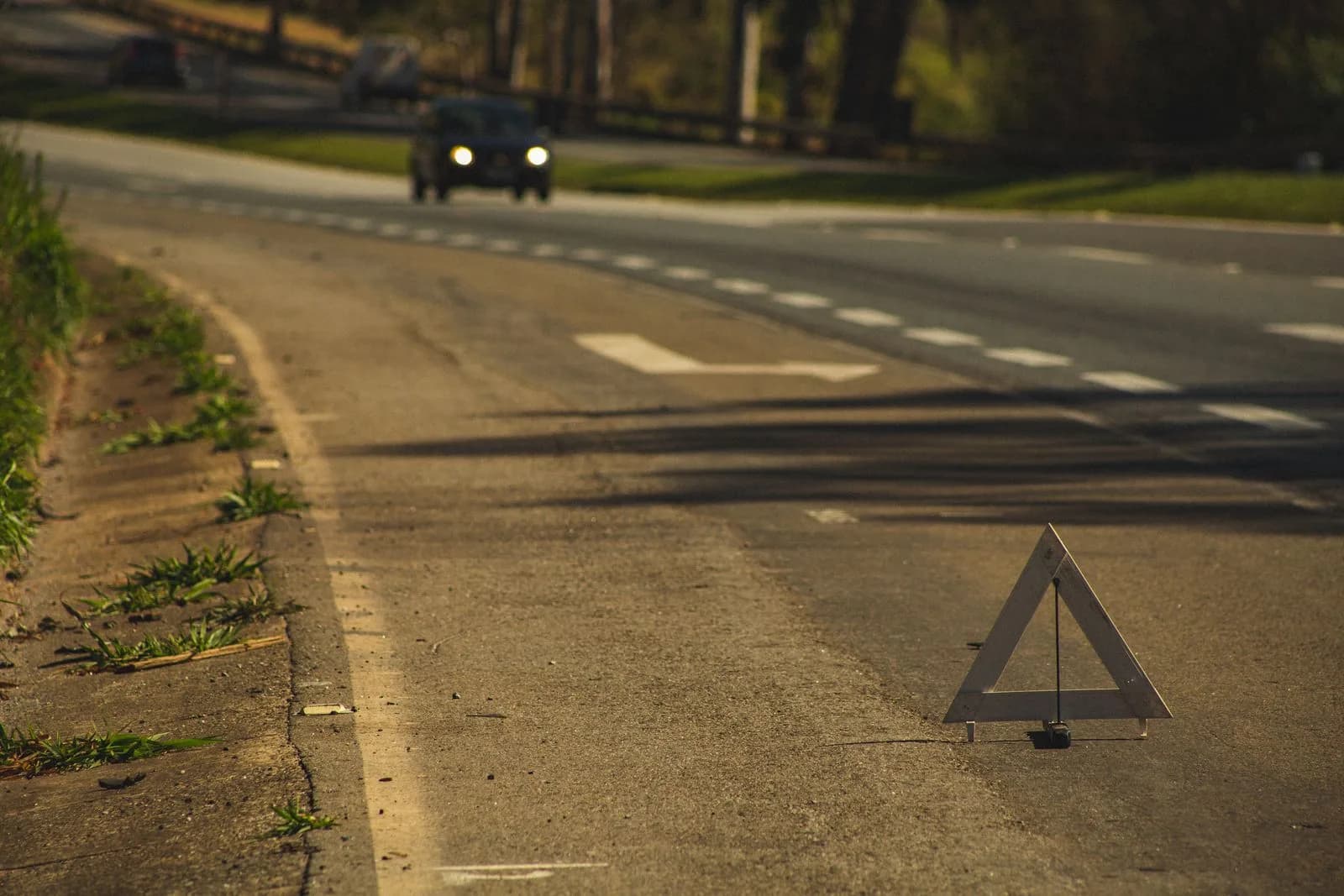 Warndreieck am Fahrbahnrand, im Hintergrund nähert sich ein Fahrzeug